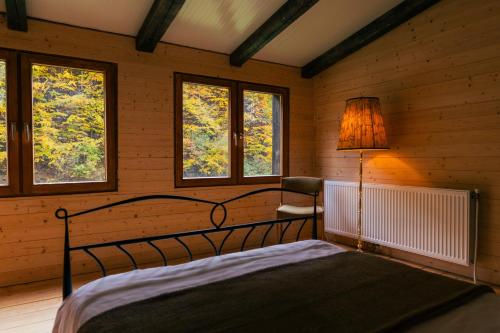 a bedroom with a bed with a lamp and windows at Cabana Murmur -Riverside- in Valea Ierii
