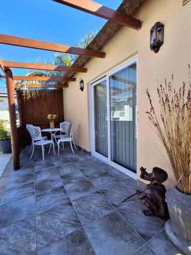 a patio with a table and chairs on it at Fynbos & Pinot Guest Cottage in Kuilsrivier