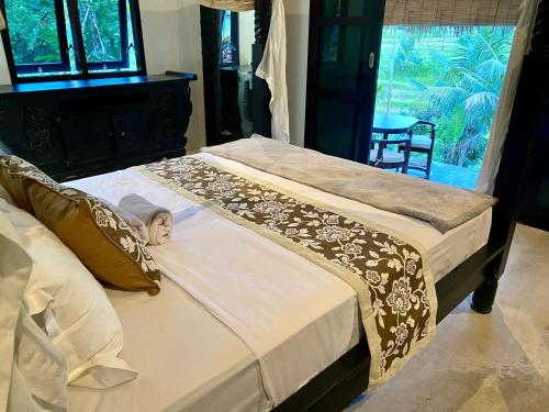 two twin beds in a bedroom with a window at The Kubu Sidemen in Silebeng