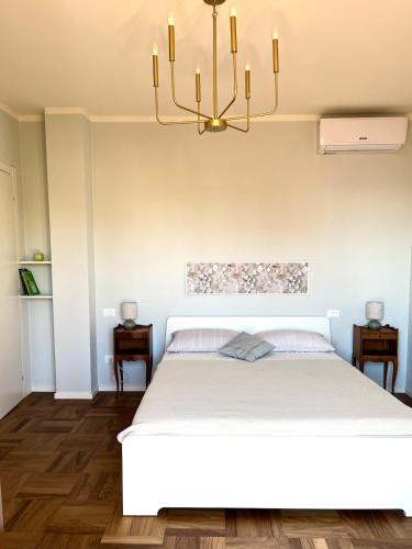 a bedroom with a white bed and a chandelier at Spacious, renovated apartment in the centre in Montecatini Terme
