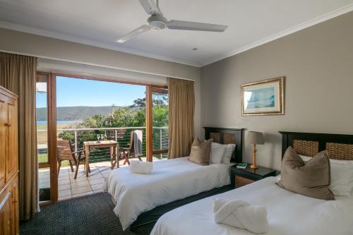 two beds in a room with a balcony at Waterfront Lodge in Knysna