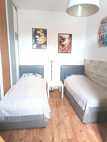 a bedroom with two beds and a table with a lamp at Centrum 2pokoje 4łożka przy MACDonald ulica Witosa 1 in Piła