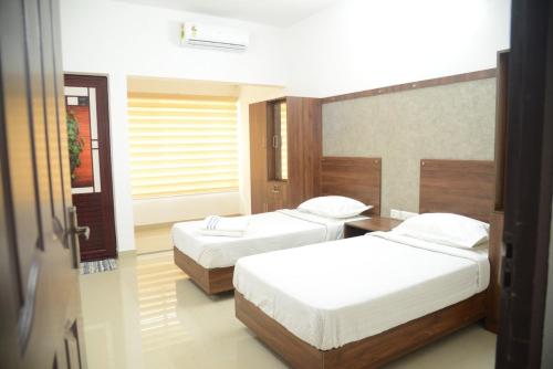 a bedroom with two beds and a window at Manna Residency in Kottayam