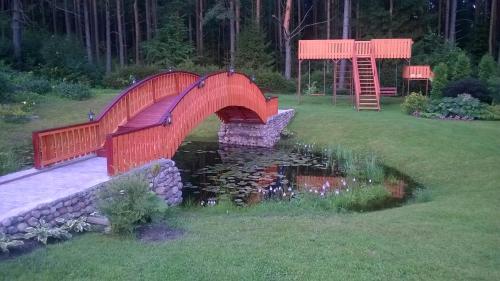 a red bridge over a pond in a yard at Oāze Smiltenē in Smiltene