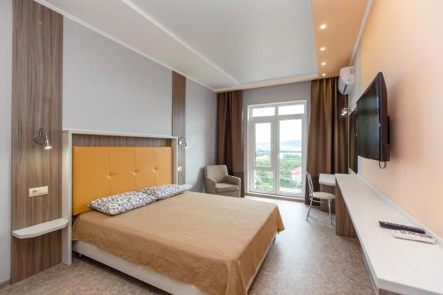 ゲレンジークにあるApartment on Khalturina 30のベッドとテレビが備わるホテルルームです。