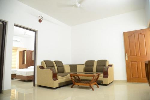 a room with two couches and a table and a bed at Manna Residency in Kottayam