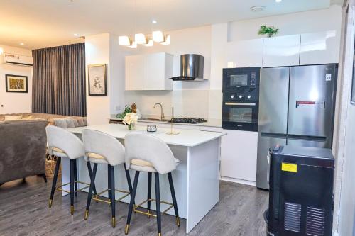 a kitchen with white cabinets and a kitchen island with stools at Jimi Comfort Stay in Bamgbose
