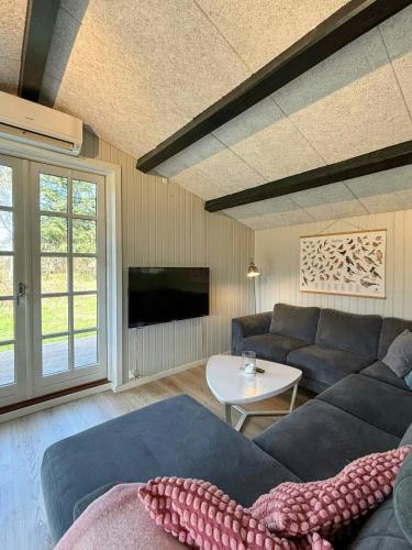 a living room with a couch and a table at Summer House With Wilderness Bath By Kårup Forest in Fårevejle