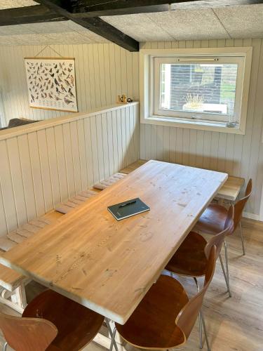 a wooden table with chairs and a laptop on it at Summer House With Wilderness Bath By Kårup Forest in Fårevejle
