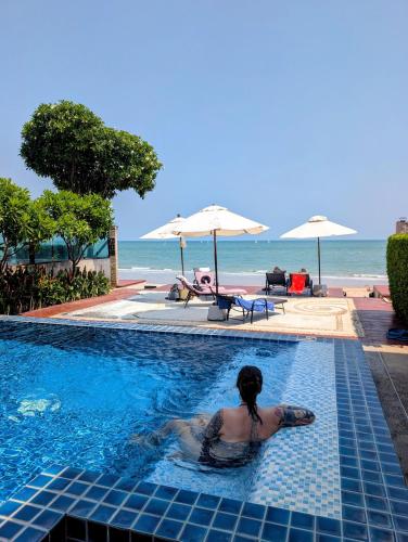 a woman swimming in a swimming pool next to the beach at Vimanlay 84m style balinais - 2 chambres - plage, piscines in Cha Am