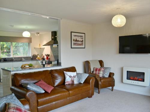a living room with a leather couch and a fireplace at Summit in Oban