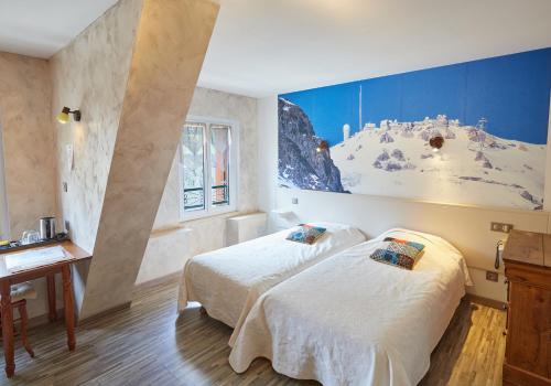 two beds in a room with a mural on the wall at Hôtel Panoramic et des Bains in Luz-Saint-Sauveur