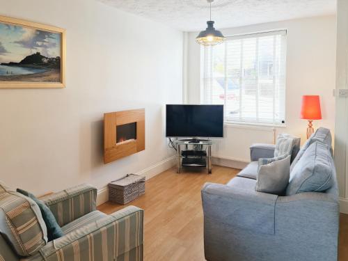a living room with two couches and a flat screen tv at Castle Street in Criccieth