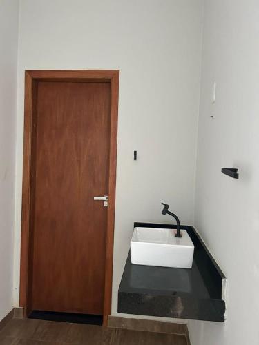 a bathroom with a sink and a wooden door at Rancho Vida Boa em Miguelopolis in Miguelópolis
