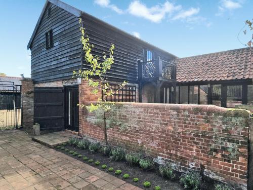a brick house with a brick wall and a building at Cartlodge Loft in Roydon