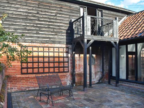 a bench sitting outside of a building with a balcony at Cartlodge Loft in Roydon