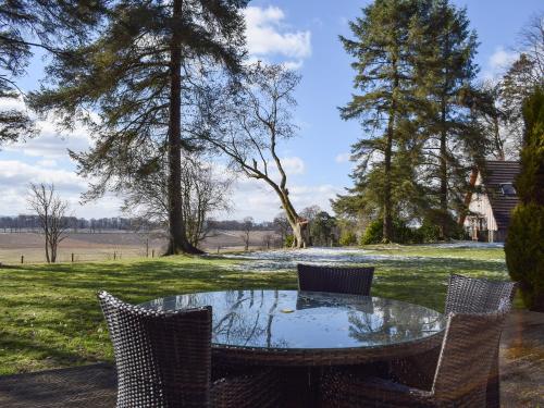 a glass table and chairs on a lawn with trees at Inzievar in Oakley