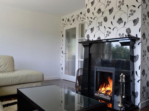 a living room with a fireplace and a couch at Carnethy in Tighnabruaich