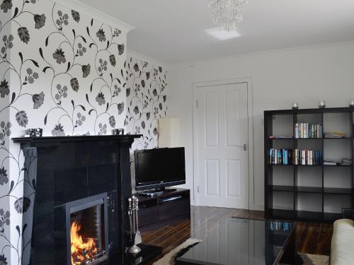a living room with a fireplace and a tv at Carnethy in Tighnabruaich