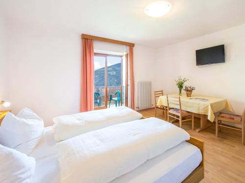 a bedroom with two beds and a table and a window at Gasthaus Gasteiger in Lagundo