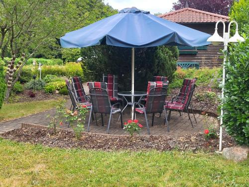 a table and chairs under an umbrella in a yard at Ferienhaus Am Sonnenhang in Zerf