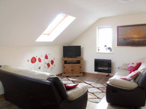 a living room with two couches and a television at Ysgubor Uchaf - 29517 in Fairbourne
