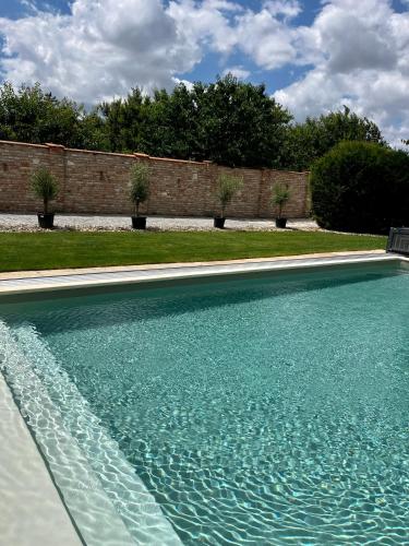a swimming pool with blue water in front of a brick wall at Hotel Garni Klaret in Valtice