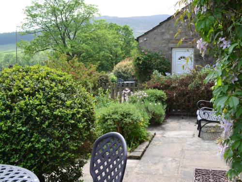 a garden with benches and bushes and a building at Clematis Cottage in Burnsall