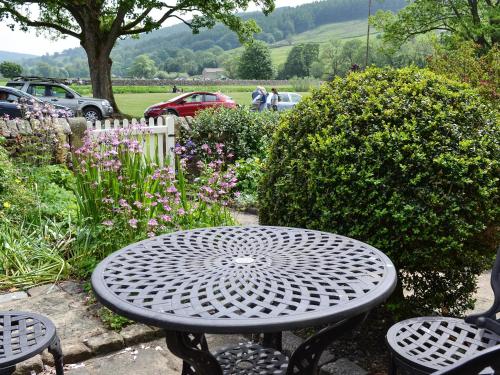 a metal table and two chairs in a garden at Clematis Cottage in Burnsall