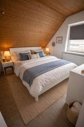 a bedroom with a large bed with a wooden ceiling at Ferienhaus Deichkrone in Dornum