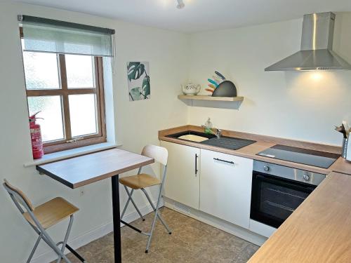 a kitchen with a table and a stove top oven at Ivy Cottage - Uk51372 in Winston