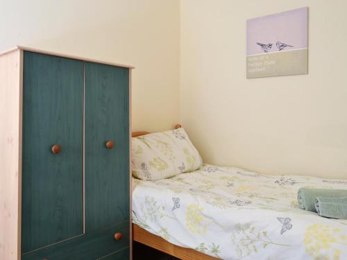 a bedroom with a green cabinet next to a bed at Hen Ysgubor - 29518 in Fairbourne