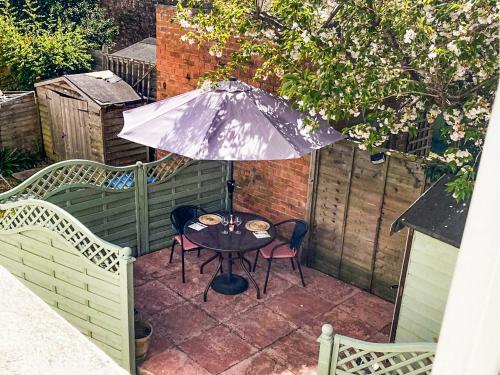 a table and chairs with an umbrella on a patio at Spire View Cottage in Olney