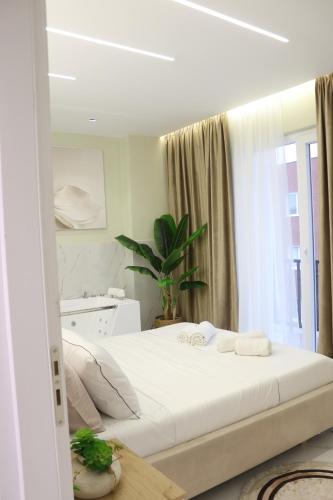 a bedroom with a large white bed with a window at SSS Luxury Apartment with Jacuzzi in Kamëz