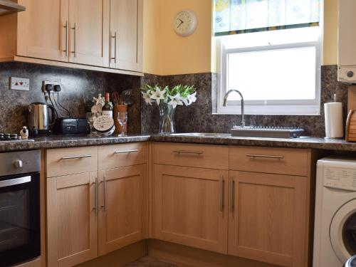 a kitchen with wooden cabinets and a sink and a window at Elm Court 7 in Keswick