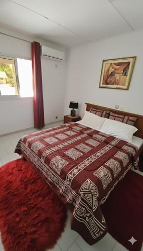 a bedroom with a large bed with a red rug at L'île de Marie-Jo in Assinie