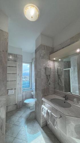 a bathroom with a sink and a toilet and a mirror at Hotel Alexander Business and Conference in Abano Terme