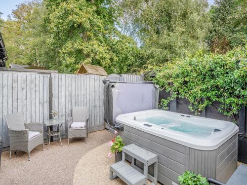 a hot tub in a backyard with a table and chairs at Shire Cottage - Uk50416 in Bisterne