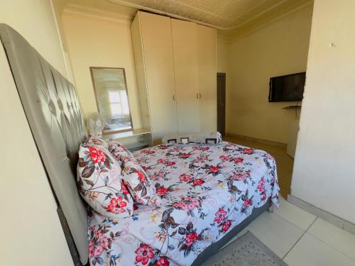 a bedroom with a bed with a floral bedspread at Le Maire Gust Lodge in Johannesburg