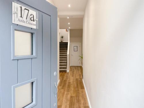 a hallway with a blue door and stairs at Airds Apartment in Oban