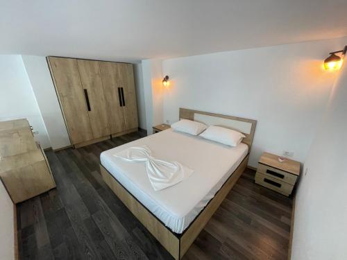 a bedroom with a bed with white sheets and wooden floors at Sea Gate Apartments in Sarandë