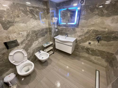 a bathroom with a toilet and a sink and a mirror at Sea Gate Apartments in Sarandë