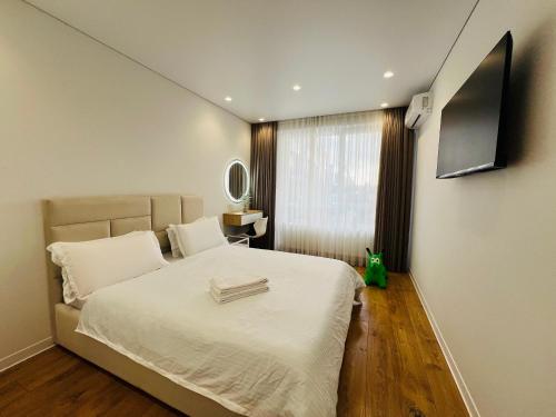 a bedroom with a bed and a flat screen tv at Apartament white in Chişinău