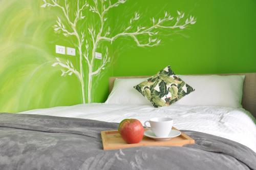 a tray with an apple and a cup on a bed at Paper Plane Hostel in Kaohsiung