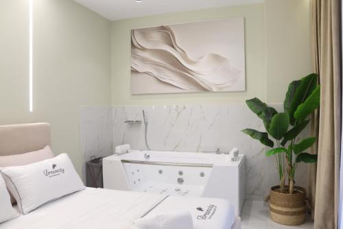a white bedroom with a bed and a plant at SSS Luxury Apartment with Jacuzzi in Kamëz