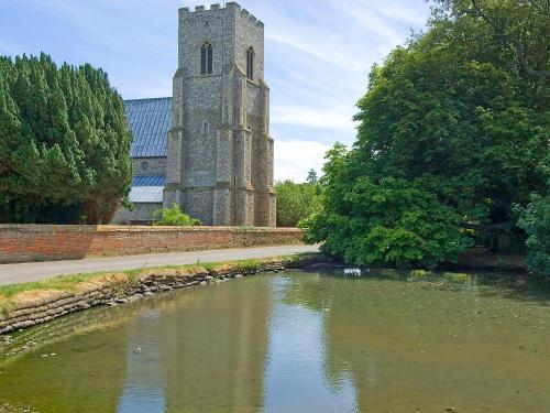 a church with a clock tower next to a river at Church View in Hunstanton