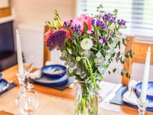 a vase filled with flowers sitting on a table at Lavender Lodge in Derby