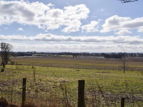 a pasture with a fence and a field with animals at Lime Tree Cottage in Oakley