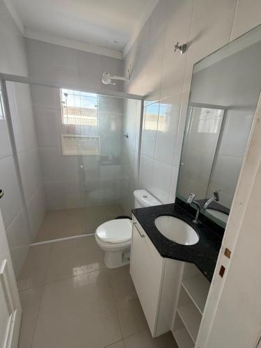 a bathroom with a toilet and a sink and a mirror at chácara 3A-2 in Pôrto Feliz