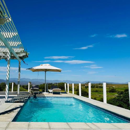 a swimming pool with an umbrella and a table and chairs at Firgrove Country House in Robertson
